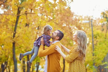 Ailesi sonbaharda sarı parkta bebekle oynuyor..