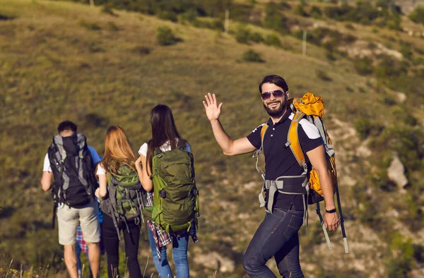 Skupina turistů s batohy kráčí podél kopce v horách v přírodě. — Stock fotografie