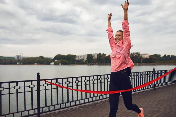 Chica corredor termina la carrera con una cinta roja . — Foto de Stock