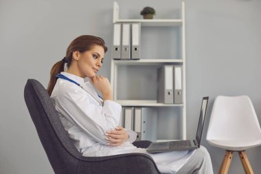 Çevrimiçi doktor. Kadın doktor, kliniğin ofisindeki web kamerası laptopunu kullanarak hastayı dinliyor..