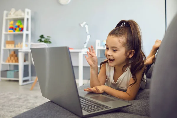 Маленькая девочка разговаривает с семьей, другом или школьным учителем онлайн из дома. Любимый ребенок, использующий ноутбук для общения — стоковое фото