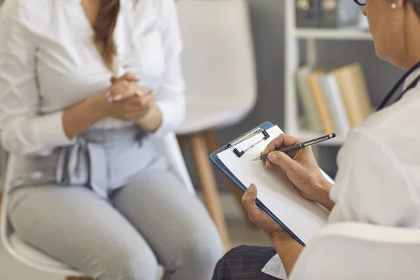 Médecin écrit une ordonnance à une patiente lors d'une consultation médicale dans une clinique. — Photo