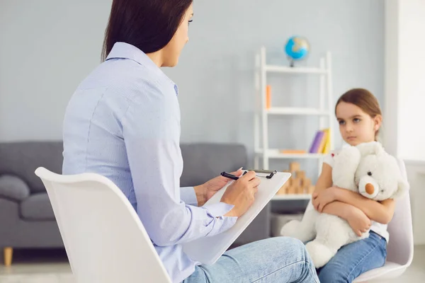 Jovem psicólogo está conversando com uma criança na sala. — Fotografia de Stock
