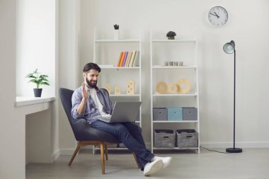 Bilgisayarlı genç adam evinden arkadaşı, iş arkadaşı ya da öğretmeniyle konuşurken el sallıyor. Uzak iletişim