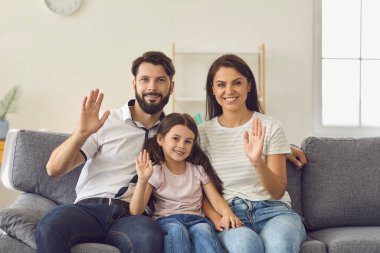 Mutlu bir aile evdeki kanepede otururken dizüstü bilgisayara bakıyor..