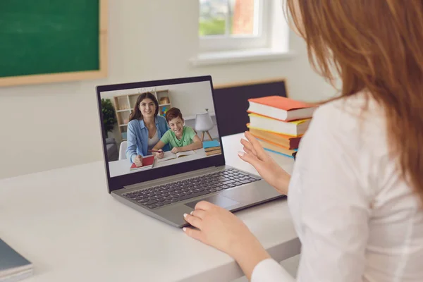 Virtuell skola. Mor och pojke lyssnar på en föreläsning av en lärare med hjälp av en bärbar dator samtal när du sitter vid ett bord hemma. — Stockfoto