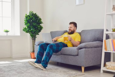 Çevrimiçi iletişim. Elinde birayla laptopta arkadaşlarıyla sohbet eden komik adam. Sakallı adam video görüşmesi yapıyor.