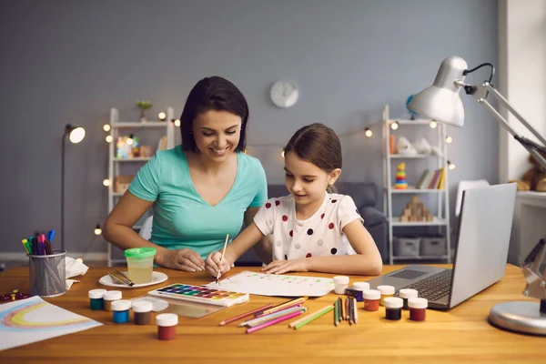 Gadis kecil mengambil kelas seni online dengan ibu membantunya di rumah. Anak dan orang tua menggambar bersama untuk video tutorial — Stok Foto