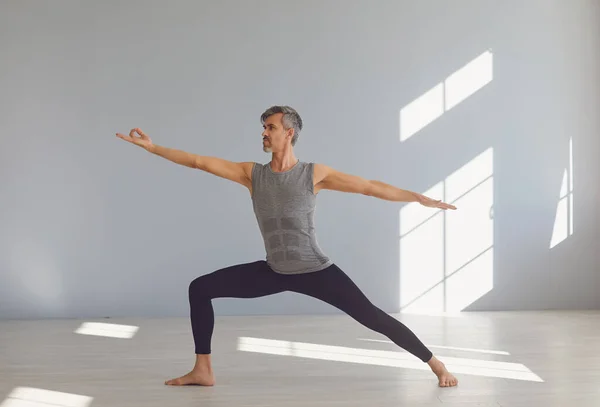 Hombre del yoga. Un hombre está practicando el equilibrio del yoga en una habitación gris. —  Fotos de Stock