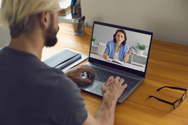 Online onderwijs en werk. Jongeman zit thuis aan zijn bureau en gebruikt videogesprek op laptop voor studie en werk. — Stockfoto