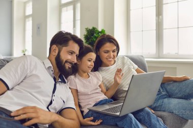 Ebeveynler ve çocuklar çevrimiçi. Güzel bir aile evde dizüstü bilgisayar izliyor..