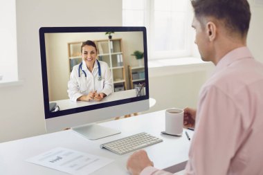 Çevrimiçi doktor. Genç bir işadamı ofisinde oturuyor ve online bir doktorun hizmetlerinden faydalanıyor..
