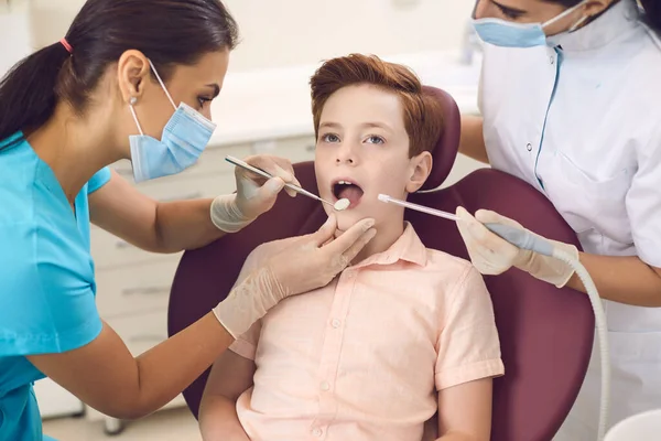 Crianças dentista dental trata um dente de menino na clínica do escritório — Fotografia de Stock