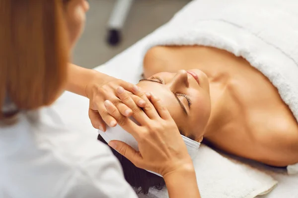 Ansiktshud skönhet och hälsa koncept. En kvinna får ansiktsmassage från en klinik. — Stockfoto