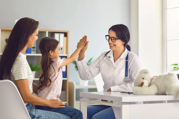 Žena doktor dává pět s rukou na malou holčičku na konzultaci na klinice. — Stock fotografie