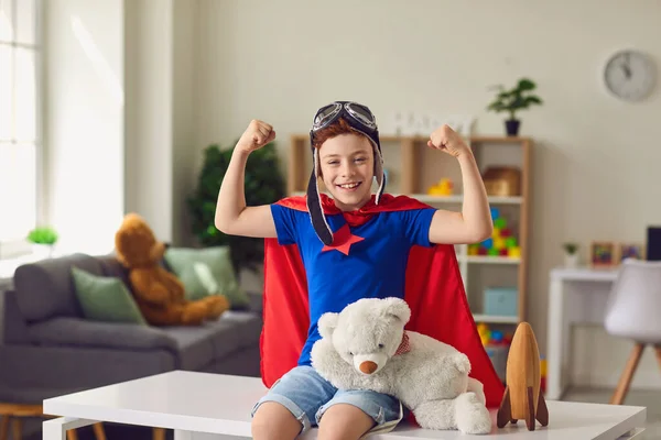 슈퍼 히어로 복장을 한 행복 한 소년이 집에서 힘을 보여 주고 있습니다. 슈퍼 맨옷을 입고 실내에서 노는 창의적 인 아이 — 스톡 사진