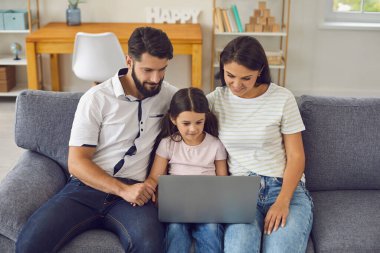 Ebeveynler ve çocuklar çevrimiçi. Güzel bir aile evde dizüstü bilgisayar izliyor..