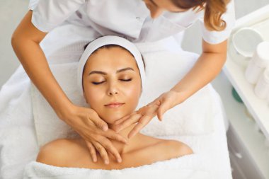Güzellik uzmanı spa salonundaki bir kadına yüz masajı yapıyor. Kadın yüz koruma programı uygulanıyor