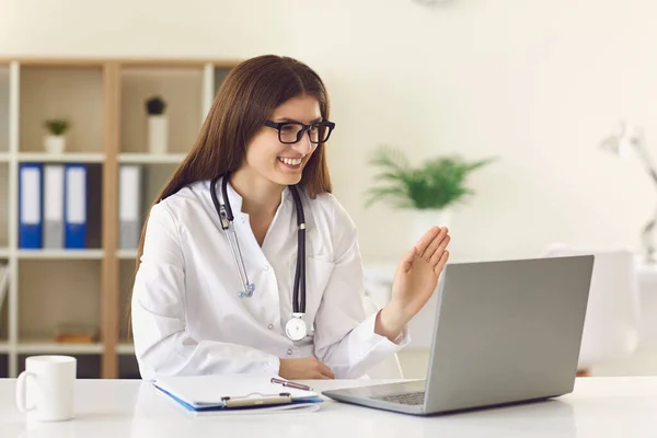 Mulher médico saudação paciente videocall on-line no laptop na clínica — Fotografia de Stock