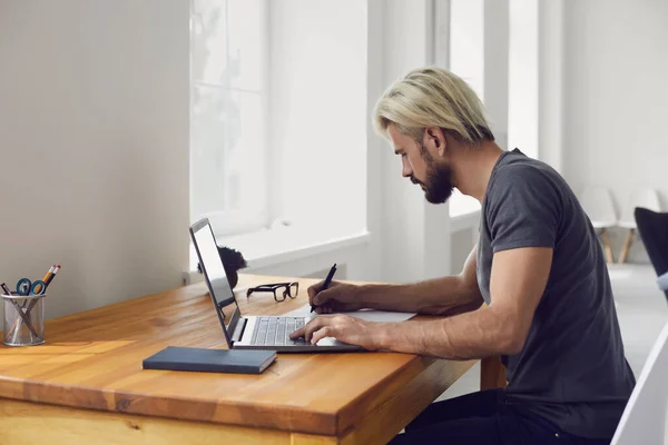 Junge Leute schreiben die wichtigsten Punkte von Online-Businesskonferenz oder Bildungs-Webinar am Schreibtisch im Haus auf — Stockfoto