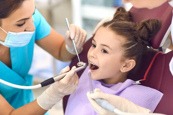 Sonriente chica consiguiendo cavidad diente cura de mujer dentista en clínica —  Fotos de Stock