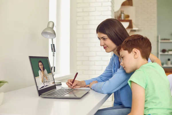 Mãe e seu filho participando de aulas on-line em casa. Pais e filhos conversando com o professor na web. Ensino à distância — Fotografia de Stock