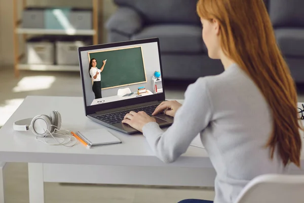Online eğitim. Evdeki masada oturan genç kız online ders için dizüstü bilgisayar kullanıyor. Üniversitede, okulda uzaktan öğrenim. — Stok fotoğraf