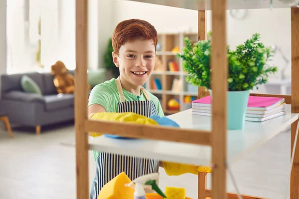 Adorable niño en guantes de goma limpiando estante con trapo en casa. Lindo niño ayudando a hacer las tareas domésticas — Foto de Stock