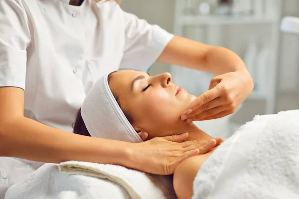 Gezichtsmassage of behandeling voor jonge vrouwen gezicht in beauty spa salon, zijaanzicht — Stockfoto