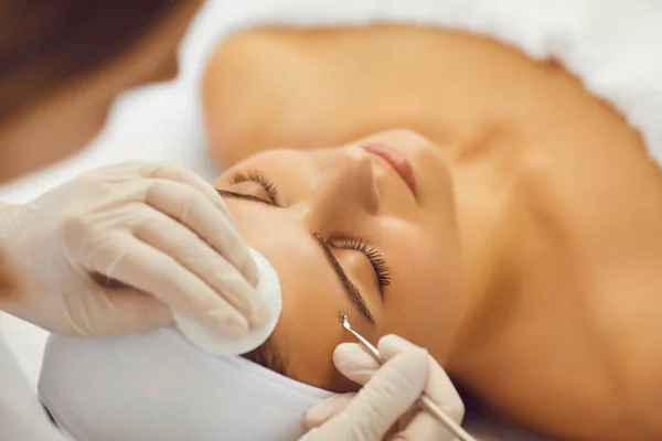 Kosmetolog czyszczący skórę dla młodej pacjentki w salonie piękności — Zdjęcie stockowe