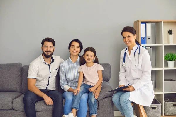 Retrato de um médico e uma família feliz estão olhando para a câmera no escritório da clínica. — Fotografia de Stock