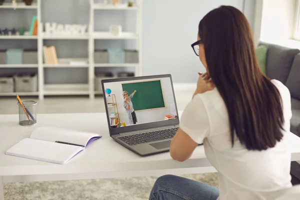 Online-Schulungen. Schülerin lauscht der Vorlesung des Lehrers hat Video-Chat-Laptop sitzt am Tisch im Zimmer. — Stockfoto