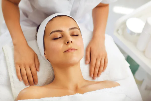 Ręce kosmetologa relaksujące się na ręczniku przy kobiecej twarzy po masażu twarzy — Zdjęcie stockowe