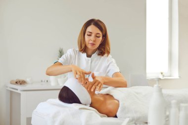 Güzellik salonunda güzellik uzmanı bir kadın için yüz masajı yapıyor.