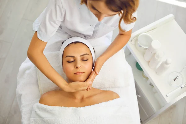 Kosmetolog podnoszący masaż twarzy dla kobiet na twarzy i szyi — Zdjęcie stockowe