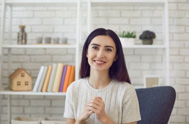 Genç kız kameraya bakıyor ve evden arkadaşı, müşterisi ya da öğretmeniyle konuşuyor. Görüntülü sohbetteki çekici kadın