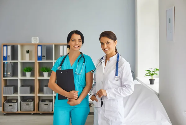 Young smiling doctor and nurse looking at camera in medical clinic — Stock Photo, Image