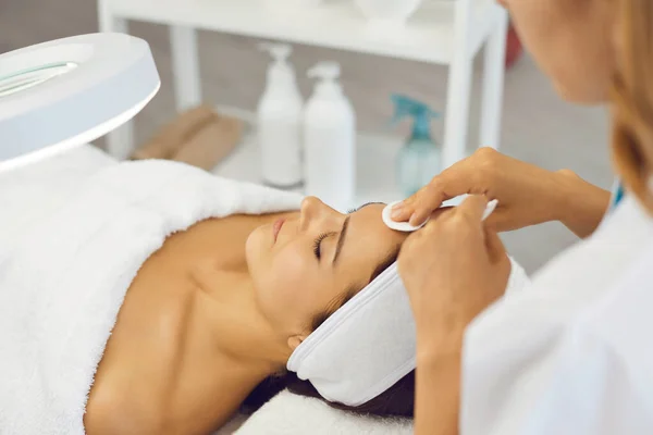 Cosmetólogo mujer limpieza de la piel facial con almohadillas de algodón antes del tratamiento de belleza — Foto de Stock