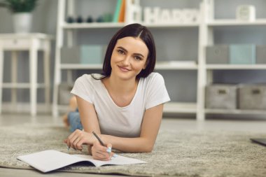 Çalışmak ya da evden çalışmak. Genç kız öğretmeniyle veya meslektaşıyla çevrimiçi iletişim kurarken kameraya bakıyor.