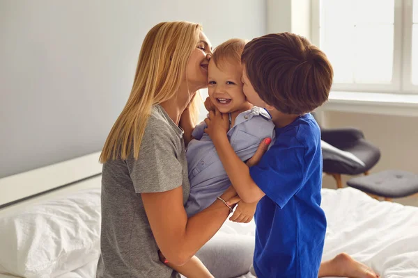 Anne ve çocuklar odada yatakta sarılıp öpüşüyorlar. Anneler Günü. Anne ve oğul kucaklaşın.. — Stok fotoğraf