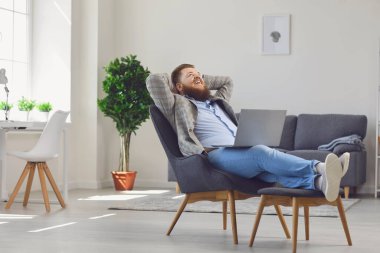 Dizüstü bilgisayarlı komik şişman adam işten sonra rahat koltukta dinleniyor. Sakallı adam tatilde evde rüya görüyor.