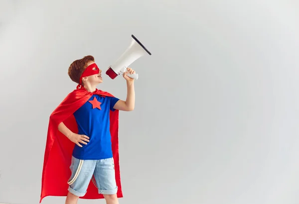 Smiling boy playing role of superhero at home with speaker in hand, copy space