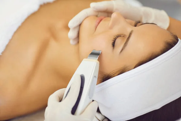 Mãos de cosmetologista fazendo ultra-som limpeza facial com máquina especial para relaxar a mulher — Fotografia de Stock