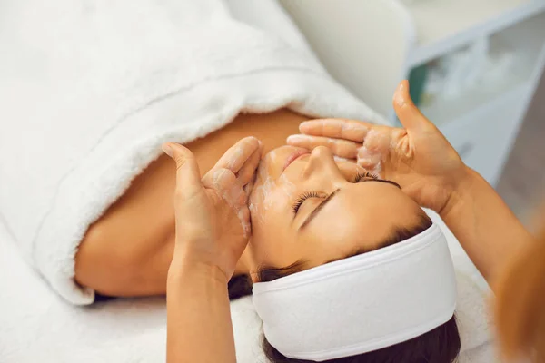Kobieta kosmetyczka sprawia, że masaż twarzy do kobiety pacjenta w salonie piękności — Zdjęcie stockowe