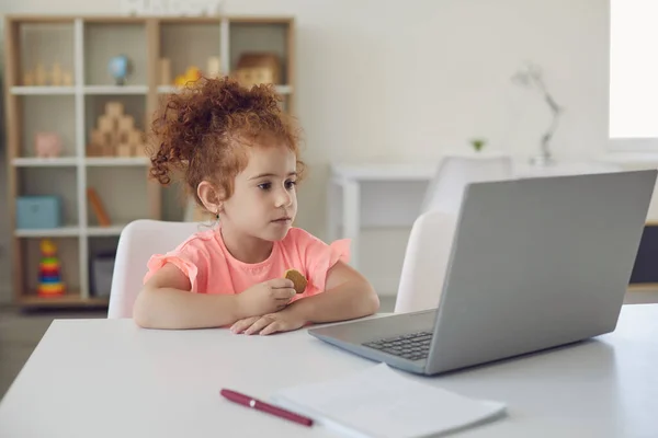 Küçük bir kız evdeki dizüstü bilgisayarında geliştirme programını izliyor. — Stok fotoğraf