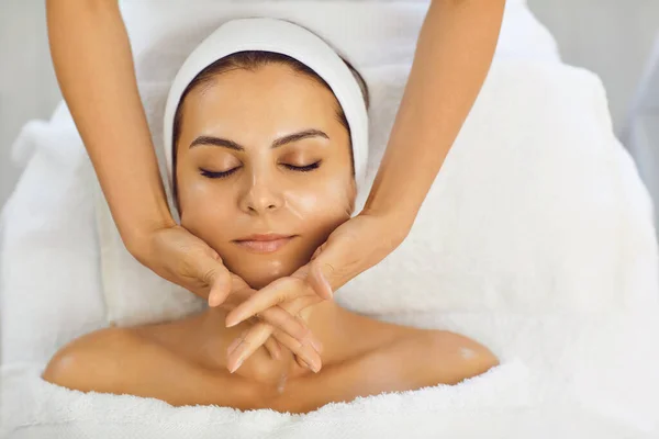 Masaje facial. El esteticista hace un masaje facial antienvejecimiento con las manos en una clínica de cosmetología —  Fotos de Stock