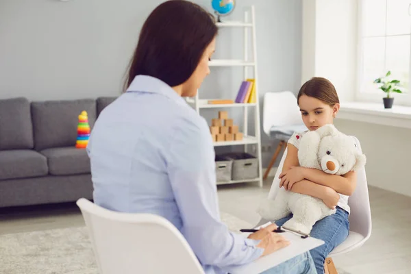 Psikolog muda sedang berbicara dengan seorang anak di dalam ruangan. — Stok Foto
