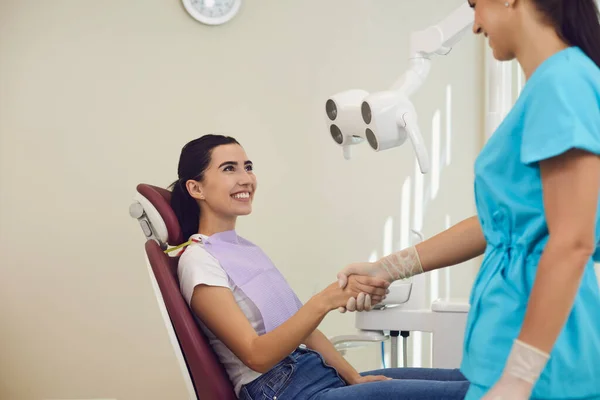 Smiling woman patient shaking hand to dentist after successful tooth examination in dental clinic — Stock Photo, Image