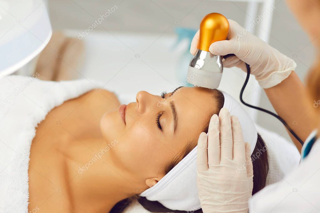 Cosmetologist making facial treatment procedure for woman in beauty salon