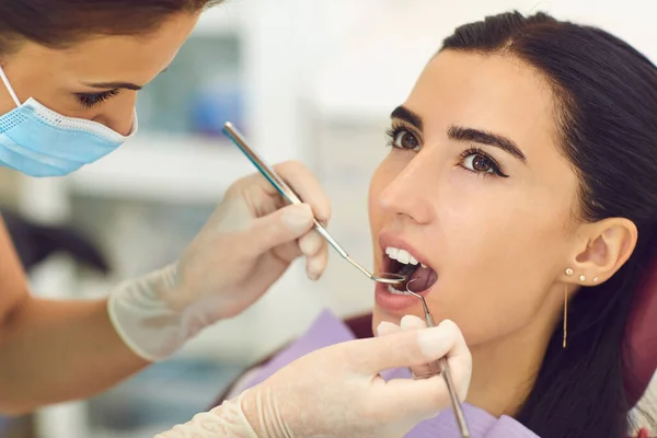 Tandarts onderzoeken vrouwelijke patiënten tand in tandheelkundige kliniek — Stockfoto